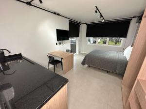 a bedroom with a bed and a desk and a kitchen at Studios 422 in Pomerode