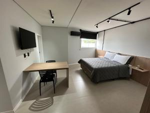 um quarto com uma cama, uma mesa e uma televisão em Studios 422 em Pomerode