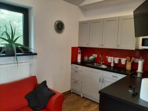 a kitchen with a red couch in a room at Apartament Rychwałd in Rychwałd