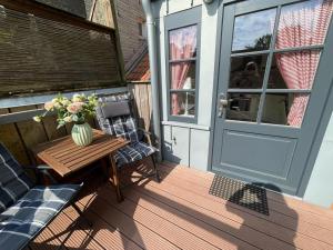 a porch with a table and a vase of flowers at Teestuuv in Husum