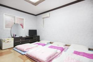 a bedroom with two beds and a dresser and a mirror at Dream of City Motel in Daegu