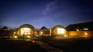 a couple of domes with lights in a field at night at Jabal shams domes in Sa‘ab Banī Khamīs