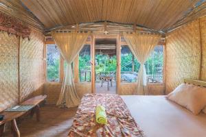 a bedroom with a bed in a room with windows at Onong's Homestay & Cafe in Tomohon