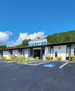 un edificio con un cartel de "Blue Sky inn" en un estacionamiento en Blue Sky Inn- Veteran Owned, New Breakfast Area, Rennovated Rooms, 5 plus acres for you and your pet to roam, NEW Fire Pit, en Blue Ridge