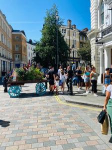 Une foule de gens marchant dans une rue avec une charrette dans l'établissement Charming central home by iconic landmarks nr, à Londres