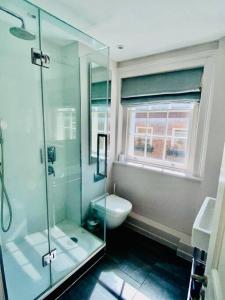 La salle de bains est pourvue d'une douche en verre et de toilettes. dans l'établissement Charming central home by iconic landmarks nr, à Londres
