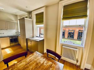 une cuisine avec une table en bois et une grande fenêtre dans l'établissement Charming central home by iconic landmarks nr, à Londres