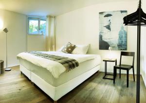 a bedroom with a large white bed and a chair at Stay at Night - Moonlight in Zürich