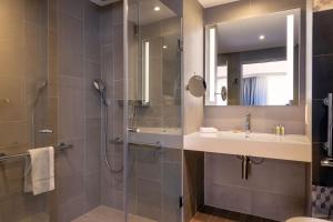 a bathroom with a shower and a sink and a mirror at Hilton Garden Inn Paris Massy in Massy