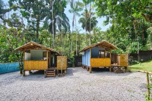 a group of cottages with chairs and trees at Refúgio na Mata Atlântica com Ofurô Aquecido in Ubatuba