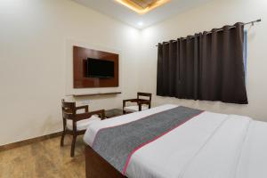 a bedroom with a bed and a tv and chairs at Townhouse Hotel Trijal Inn in Lucknow