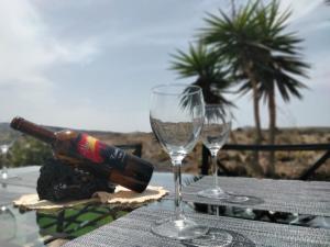 two wine glasses and a bottle on a table at LANZAROTE Casa Volcánica-Anclada sobre la lava del volcán in Montaña Blanca
