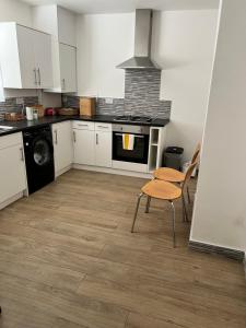 a kitchen with white cabinets and a stove and a chair at Brand new cosy studio apartment in West Dulwich