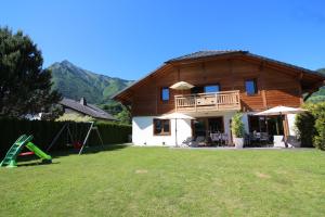 a wooden house with a yard with a playground at Gîte Balnéo Au Coeur des Alpes in Taninges