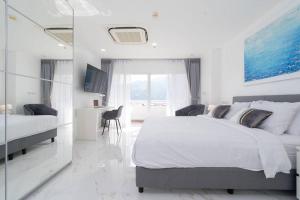 een witte slaapkamer met een groot bed en een bureau bij Patong Tower Brand New 1-Bedroom , Near Beach in Patong Beach