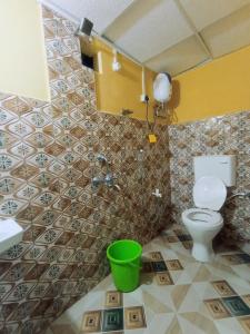 baño con aseo y cubo verde en Jungle view homestay, en Mādāri Hāt