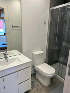 a white bathroom with a toilet and a shower at Golden Place - Cacilhas in Almada
