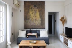 una sala de estar con un sofá azul y una pintura en The Terrace Kiss, en Atenas