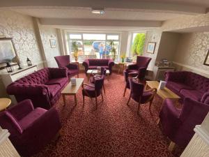 a waiting room with purple couches and chairs at Monarch Hotel in Bridlington