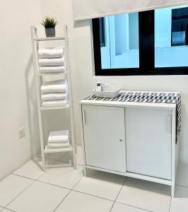 a white bathroom with a sink and a stack of towels at PadiViu Family Suite at Imperio Professional Suite, Alor Setar in Alor Setar