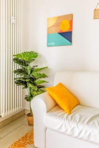 a white couch with a yellow pillow and a plant at La finestra sulla fiera in Bologna