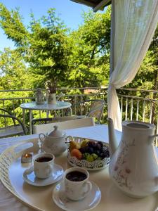 a table with cups of coffee and a bowl of fruit at Villa Chingo in Ohrid