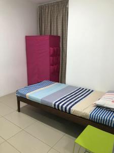 a small bed in a room with a green chair at M1 Budget Comfortable Central in Kuching