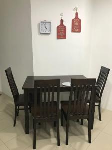 mesa de comedor con sillas y reloj en la pared en M1 Budget Comfortable Central en Kuching