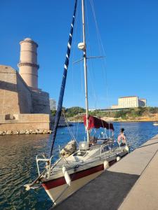 una barca a vela legata a un molo con un faro sullo sfondo di Voilier à quai a La Londe-les-Maures