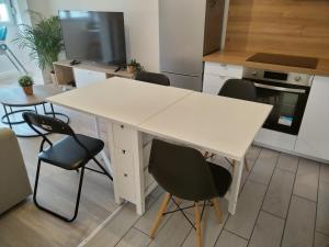 - une cuisine avec une table et des chaises blanches dans l'établissement KEZA's Apartment - Strasbourg, à Strasbourg