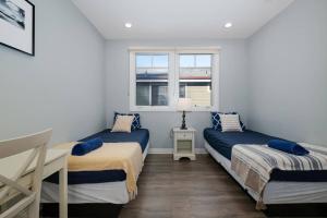 two beds in a room with two windows at Comfy 4BR home near Korea Town in Los Angeles