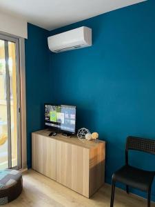 ein Wohnzimmer mit einem TV und einer blauen Wand in der Unterkunft Studio Bord de Mer Boulouris à Saint Raphael in Saint-Raphaël