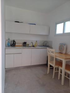 cocina con armarios blancos y mesa de madera en יחידת דיור נפרדת עמק המעיינות בית שאן en Bet Sheʼan