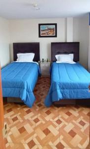 two beds in a room with blue comforters at A y J Familia Hospedaje in Lima