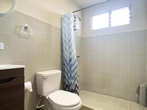 a bathroom with a toilet and a blue shower curtain at Cata Bed Breakfast Pet-friendly in San José +69 photos