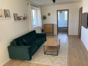 a living room with a green couch and a table at Apartmán 696 Pod Ještědem in Liberec