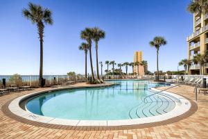 a large swimming pool with palm trees and a building at Grand Panama by Panhandle Getaways in Panama City Beach