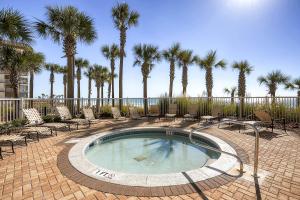 a swimming pool with chairs and palm trees at Grand Panama by Panhandle Getaways in Panama City Beach