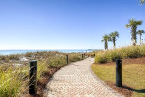 a brick path leading to the beach with palm trees at Grand Panama by Panhandle Getaways in Panama City Beach