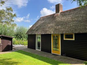 a black house with a thatched roof at Oasis holiday home in Giethoorn next to canal, boat extra in Giethoorn