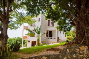 a white house with trees in front of it at Mikoko Beach & Cottages in Bagamoyo