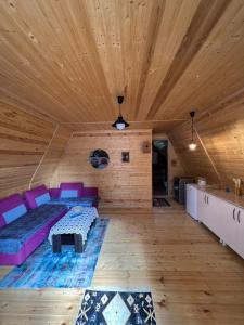 una sala de estar con sofá púrpura y techos de madera. en Cottage Mida en Mestia
