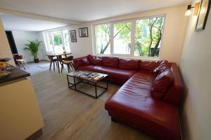 sala de estar con sofá de cuero rojo y mesa en B&B Alferweiher, en Echternach