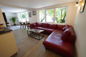 a living room with a red leather couch and a table at B&B Alferweiher in Echternach