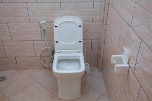 a bathroom with a toilet with the lid up at Mikoko Beach & Cottages in Bagamoyo