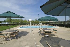 a patio with tables and umbrellas next to a pool at The Rockville Hotel, a Ramada by Wyndham in Rockville