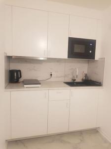 a white kitchen with a microwave and a sink at Wohnung Daria in Neu-Anspach