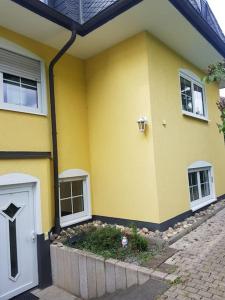 une maison jaune avec une porte blanche et des fenêtres dans l'établissement Wohnung Daria, à Neu-Anspach