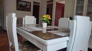 a white dining room table with white chairs and flowers at Apartamento Turistico Centenario in Montenegro