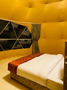 Ce lit se trouve dans une chambre dotée d'un mur jaune. dans l'établissement Syndebad desert camp, à Wadi Rum